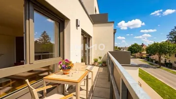 Möblierter Balkon mit Blick auf die Umgebung und blauen Himmel, ideal zum Entspannen.