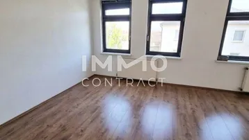 Geräumiges Schlafzimmer mit dunklem Holzboden und Blick ins Grüne.