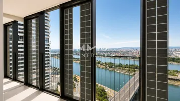 Heller Innenraum mit raumhohen Fenstern und weitem Blick über die Stadt und den Fluss.