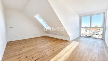 Helles Dachzimmer mit Holzboden, großen Fenstern, Dachschräge und viel natürlichem Licht.
