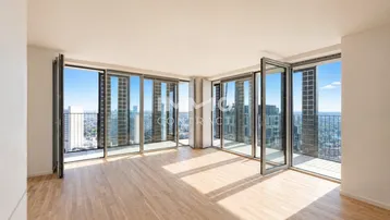 Helles Wohnzimmer mit Parkettboden, raumhohen Fenstern und weitem Stadtblick.