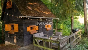 Gemütliche Holzhütte im Wald mit einer möblierten Holzterrasse und Lichterkette.