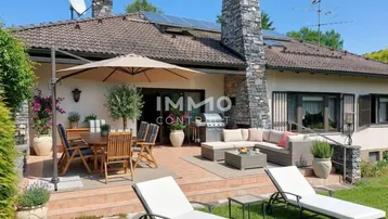 Große Sonnenterrasse mit Ess- und Loungebereich, umgeben von einem gepflegten Garten und mit Solaranlage auf dem Dach.