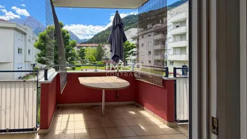 Geräumiger Balkon mit Bergblick, gefliestem Boden und kleinem Tisch mit Sonnenschirm.