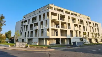 Modernes Mehrfamilienhaus mit mehreren Balkonen und klarer Architektur in städtischer Umgebung.