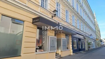 Fassade eines historischen Gebäudes mit Geschäften im Erdgeschoss und großen Fenstern.