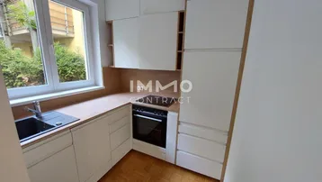 Moderne kleine Küche mit weißen Schränken, Holztheke, integriertem Ofen und Blick ins Grüne.