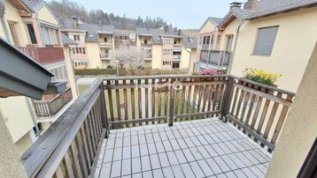 Balkon mit Holzbalken und Fliesenboden, bietet einen Blick auf die umliegenden Wohngebäude.