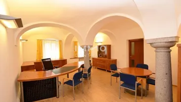 Geräumiges Büro mit gewölbten Decken, Holzböden und mehreren Arbeitsplätzen.