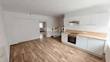 Helle, offene Küche mit weißen Schränken, Holzarbeitsplatte und modernem Laminatboden.