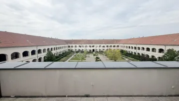 Weitläufiger Blick von der Terrasse auf den großen, begrünten Innenhof der historischen Anlage.