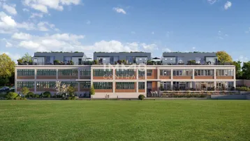 Moderne Wohnanlage mit großen Fenstern und Dachterrassen, umgeben von Grünflächen unter blauem Himmel.