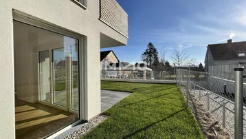 Sonniger Außenbereich mit Terrasse, Rasen und Blick auf die ländliche Umgebung.