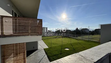 Balkon mit Holzgeländer bietet einen weiten Blick über die grüne Umgebung und den blauen Himmel.