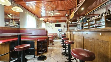 Gemütliche Bar mit Holztäfelung, roten Lederhockern und traditioneller Einrichtung, ideal für gesellige Abende.