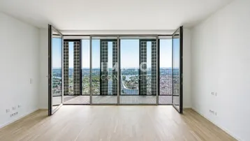 Helles Zimmer mit Holzboden und raumhohen Fenstern, die einen weiten Stadt- und Wasserblick bieten.