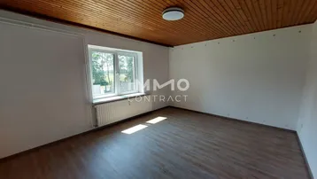 Helles Zimmer mit Laminatboden, Holzdecke und Blick ins Grüne.