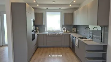 Moderne Einbauküche in Grau mit integrierten Geräten, viel Stauraum und einem Fenster.