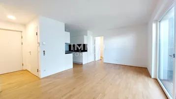 Heller offener Wohnbereich mit Holzboden und Zugang zu einem Balkon oder einer Terrasse.