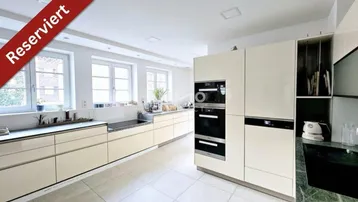 Moderne Küche mit hellen Einbauschränken, integrierten Geräten und großen Fenstern für viel Tageslicht.
