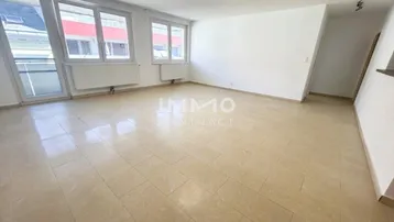 Helles, leeres Wohnzimmer mit Fliesenboden und großen Fenstern, bereit zur individuellen Gestaltung.