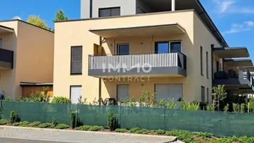 Modernes Mehrfamilienhaus mit Balkonen und zeitgenössischer Architektur unter blauem Himmel.