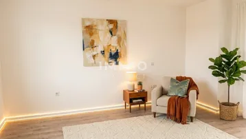 Helles Wohnzimmer mit moderner indirekter Beleuchtung, einem Sessel und einem dekorativen Wandbild.