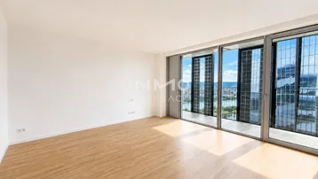 Helles Wohnzimmer mit großen Fenstern, Holzboden und weitem Blick auf die Stadt und das Wasser.