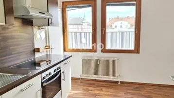 Küche mit Einbaugeräten, Laminatboden und Fenstern mit Blick nach draußen.