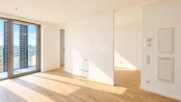 Helles, leeres Wohnzimmer mit Holzboden und großen Fenstern, die einen weiten Stadtblick bieten.