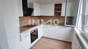 Moderne Einbauküche mit weißen Schränken, Holzoptik-Arbeitsplatten und einem Fenster für natürliches Licht.