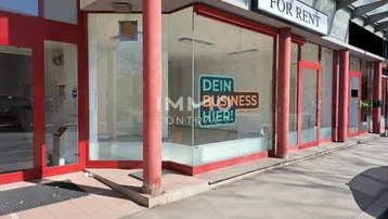 Vorderansicht eines Geschäftsgebäudes mit großen Schaufenstern und roten Akzenten, bereit zur Vermietung.