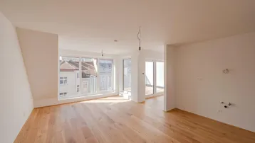 Helles Wohnzimmer mit Holzboden und Zugang zu einer Terrasse, bietet viel natürliches Licht.