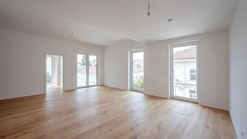 Helles, leeres Wohnzimmer mit neuem Holzparkettboden und Zugang zu mehreren Fenstern.
