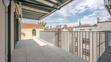 Geräumiger Balkon mit Fliesenboden und Blick auf die umliegenden Gebäude der Stadt.