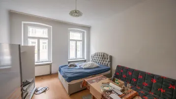Helles Zimmer mit Bett, Sofa und Holzfußboden, ideal für ein Studio-Apartment.