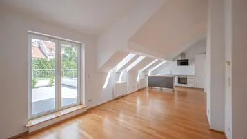 Heller offener Wohnbereich mit Holzboden, Dachschrägen und Zugang zu einer Terrasse.