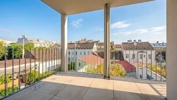 Geräumiger Balkon mit Fliesenboden und weitem Blick über die Stadt und umliegende Dächer.