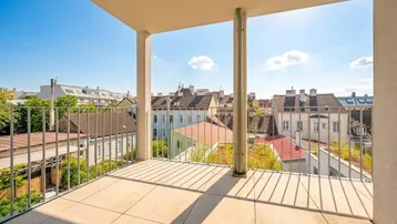 Sonniger Balkon mit Fliesenboden und weitem Blick über die Dächer der Stadt.