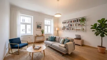 Helles Wohnzimmer mit Holzboden, bequemen Möbeln und Bücherregal, das eine gemütliche Atmosphäre schafft.