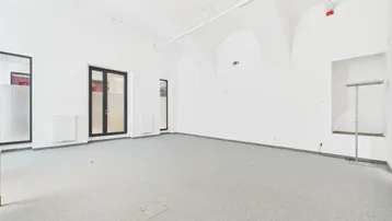 Geräumiger, heller Gewerberaum mit gewölbter Decke, Teppichboden und großen Fenstern.
