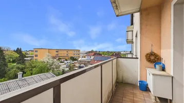 Balkon mit Fliesenboden, kleiner Ablage und weitem Blick über die Umgebung.
