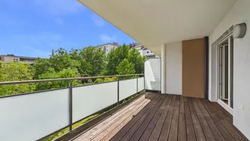 Geräumiger Balkon mit Holzboden und Blick ins Grüne, ideal zum Entspannen.