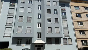 Mehrstöckiges Wohngebäude mit hellblauer Fassade, vielen Fenstern und Balkonen.