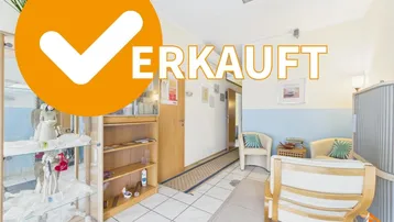Heller Empfangsbereich mit Fliesenboden, Sitzgelegenheiten und Vitrinen, der einen gepflegten Eindruck macht.