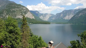 Panoramablick auf den See und die umliegenden Berge unter blauem Himmel.