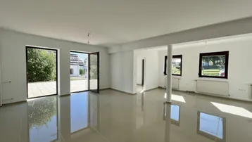 Großzügiger Wohnraum mit Fliesenboden und doppelten Terrassentüren für viel Tageslicht.