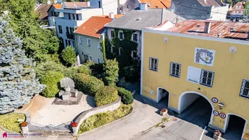 Luftaufnahme einer historischen Stadtansicht mit grünen Bäumen und traditionellen Dächern.