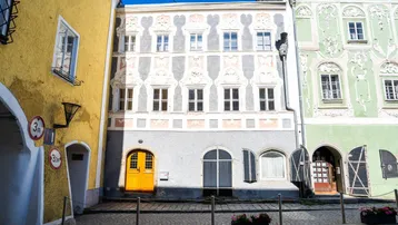 Historische Fassade eines Gebäudes mit kunstvollen Verzierungen und einer leuchtend gelben Eingangstür.