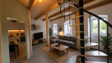 Helles, offenes Wohnzimmer mit Wendeltreppe, Holzbalken und Blick auf die moderne Küche.